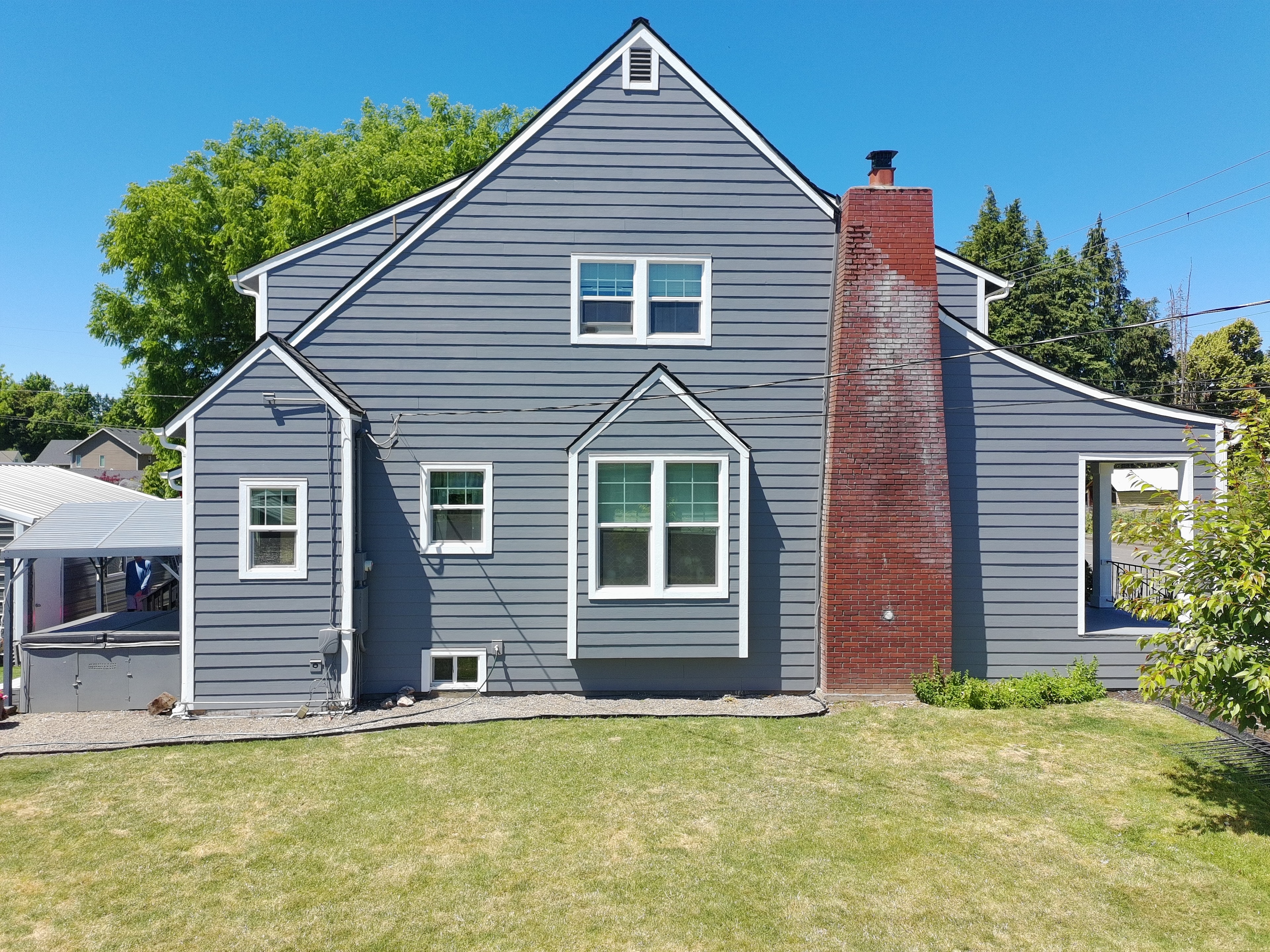 Completed gray James Hardie siding with white trim and red brick chimney — Stayton Oregon